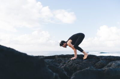 Energetic man in tracksuit doing balance Pose during yoga exercises in morning