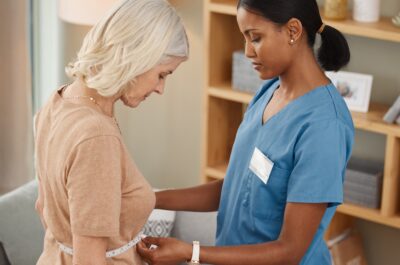 Shot of a doctor using a measuring tape on a senior womans stomach during a consultation at home